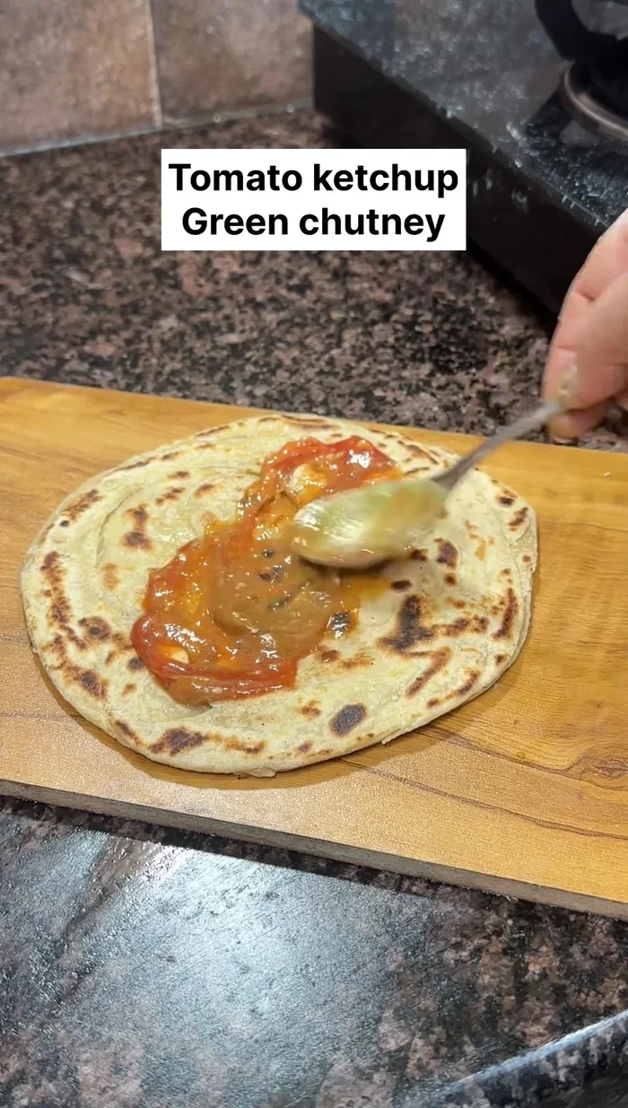 Assemble the roll: Spread tomato ketchup and green chutney on the roti. Add the paneer and vegetable mixture, onions, more green chutney, lemon chaat masala, and optional green chilies and coriander.