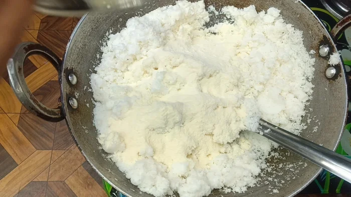 Add two bowls of sugar (using the same bowl as for coconut powder). Cook well, mixing everything, with the gas flame on medium.