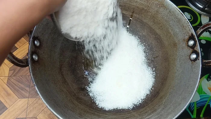 Let the ghee melt. Add four bowls of desiccated coconut powder and fry for 2 minutes while stirring, keeping the gas flame on low.