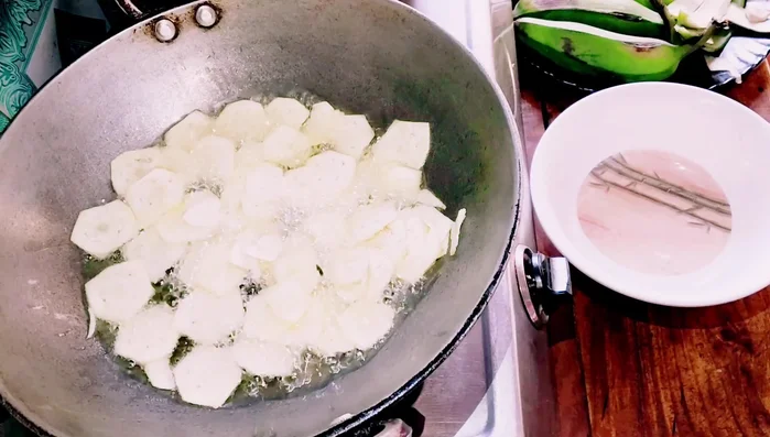 Add the banana chips to the hot oil. Add two spoons of salt water to the pan.