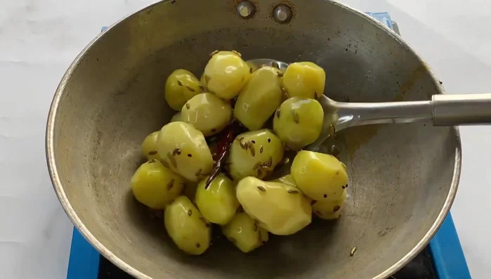 Add the peeled potatoes to the pan and fry them until well-browned, adding a little turmeric powder.