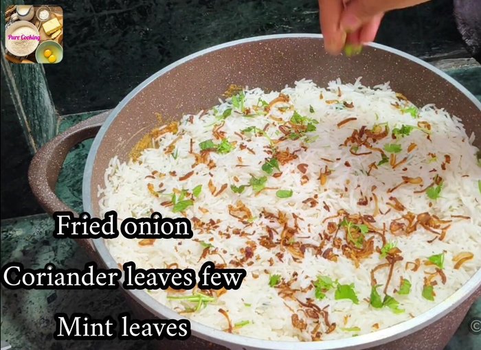 Add the remaining fried onions, chopped coriander and mint leaves, the juice of one lemon, the saffron milk, 50 grams of ghee, and the remaining oil from frying the onions.