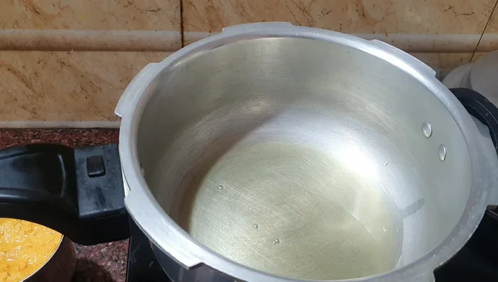 Heat cooking oil in a cooker. Add mustard seeds and lentils; fry until they splutter.