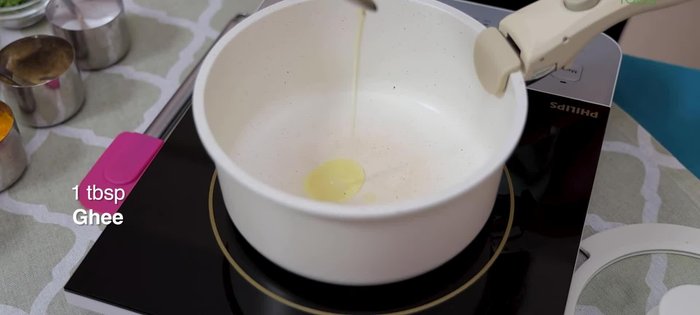 Add 1 tbsp ghee to a hot pan. Once heated, add 1 cardamom and a few peppercorns.