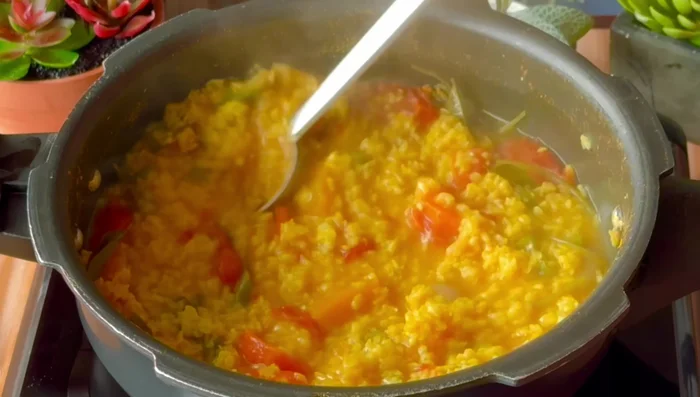 Once the steam releases, open the cooker and gently mash the dal, ensuring carrots are not overcooked. Do not over mash.