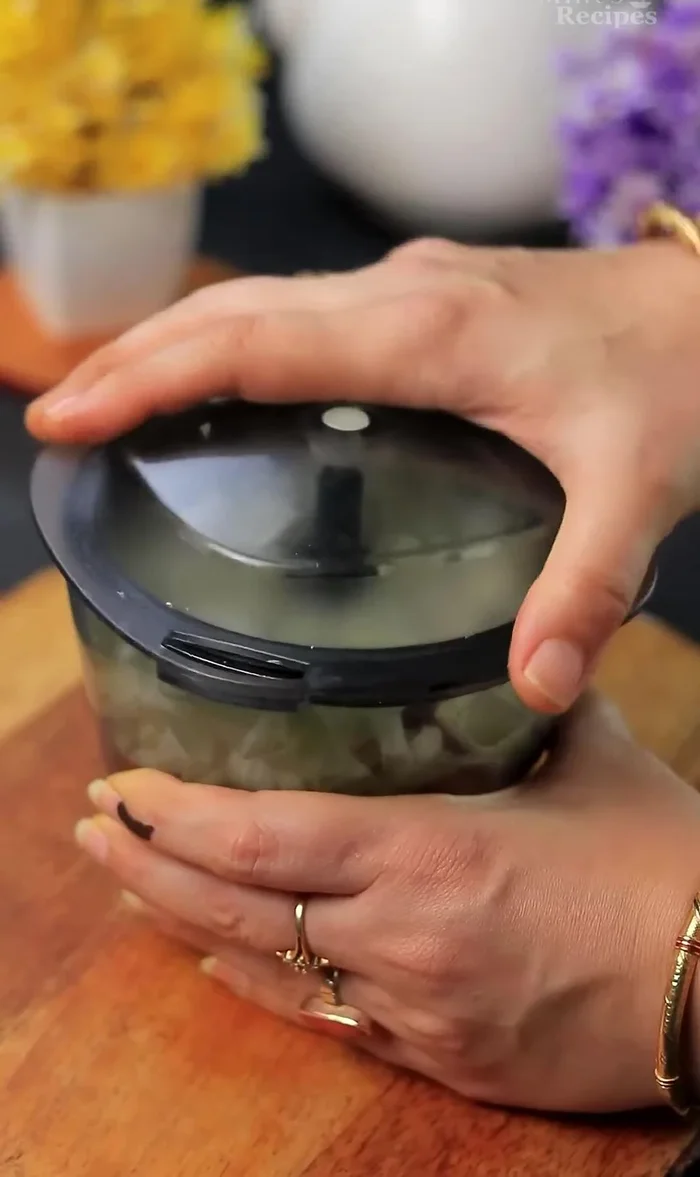 Finely chop carrots, onion, and cabbage using a chopper.