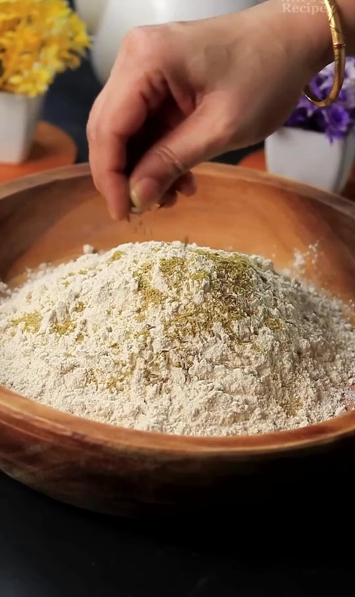 In a bowl, mix wheat flour with coriander powder, cumin seeds, celery, mango powder, garam masala, chili flakes, salt, and Kasuri Methi.