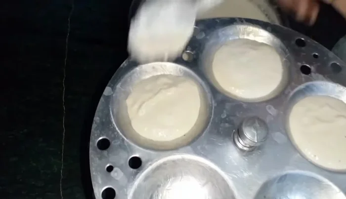 Pour the batter into the idli moulds, leaving some space at the top.
