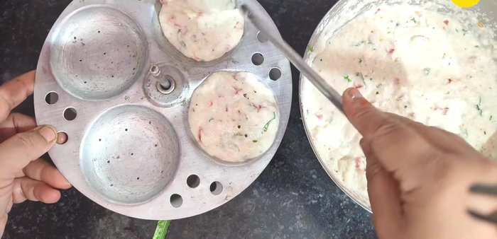 Pour the batter into the idli moulds. Garnish with Kashmiri red chilli and green coriander.