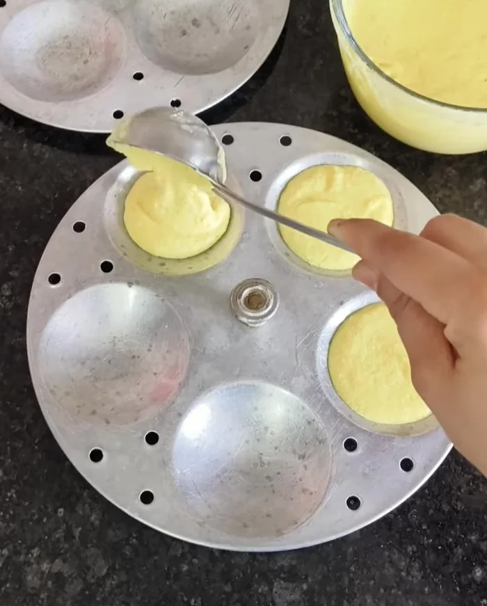 Pour the batter into the prepared idli molds, filling them about ¾ full.