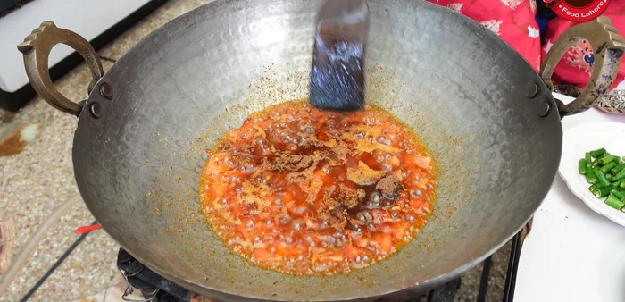 Gradually add the reserved lentil water while continuously stirring the spices, creating a Dhaba style flavor.