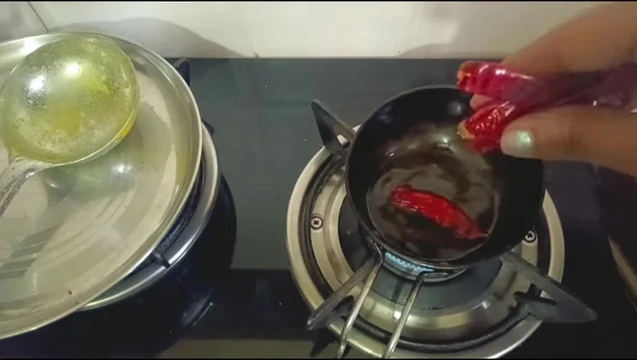 Prepare double tadka: Heat oil, add dried red chilies, asafoetida, curry leaves, red chili powder, and sambar masala. Pour over the sambar.