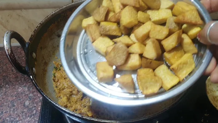 Add the fried yam pieces to the spice mixture. Mix well to coat the yam evenly.