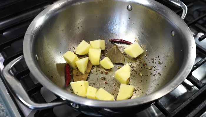 Add chopped potatoes and 1/2 teaspoon of hing (asafoetida). Fry for a minute on medium heat, then lower the heat and add the spice paste. Stir for about a minute.