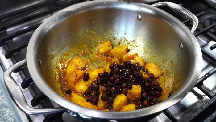 Add the boiled kala chana, 2 tbsp of grated coconut, and stir for a minute. Add 1/2 teaspoon of salt and 1/2 cup of hot water. Cover and simmer until the potatoes are nearly tender (about 8 minutes).