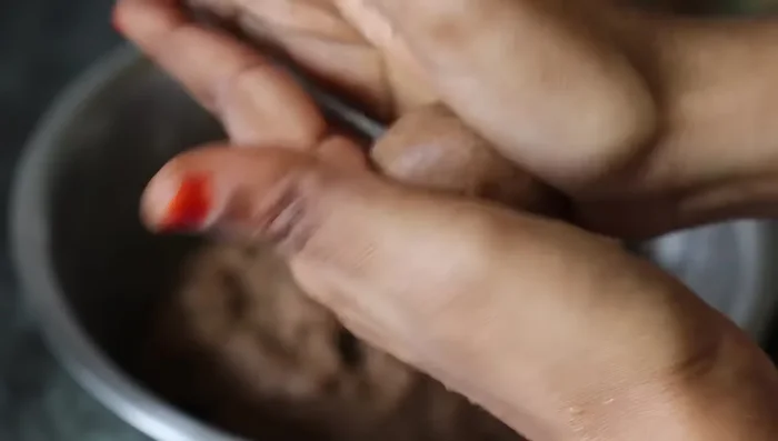 Take small balls of dough and roll them into laddu-sized circles without any cracks. You can optionally use a knife to create designs on the biscuits.