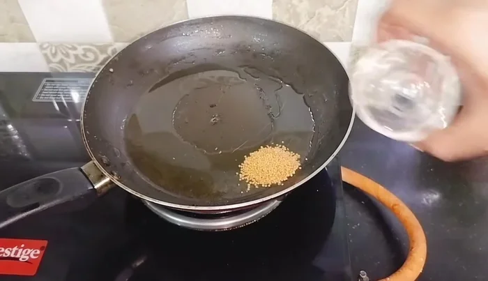 Prepare tadka: Heat oil, add mustard seeds, urad dal (immediately after washing), dried chilies, and curry leaves. Fry until they crackle.