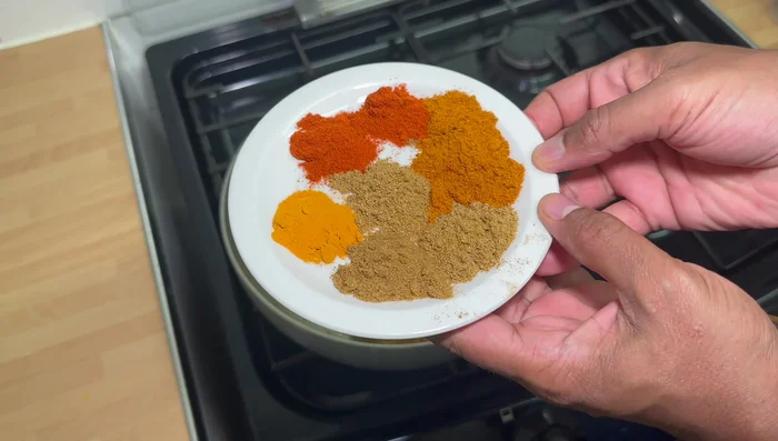 Add ground coriander powder, ground curry powder, Kashmiri red chili powder, ground cumin powder, and ground turmeric powder. Cook for 20-30 seconds to toast the spices.