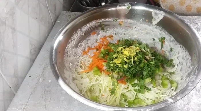 Add chopped vegetables, asafoetida, coriander powder, turmeric powder, and chili powder to the batter. Mix well.