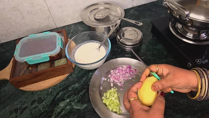 Prepare the raita: Chop onions, cucumber, and boiled potato. Mix with whipped curd, coriander-mint chutney, cumin powder, and black salt.