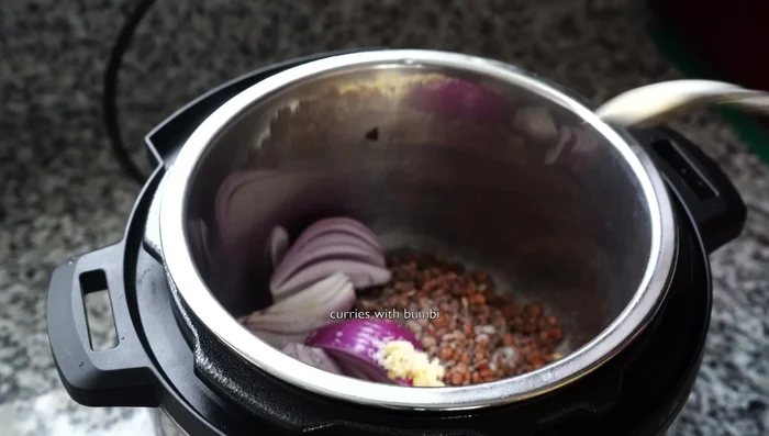 Add chopped onion, grated ginger, salt, turmeric powder, cumin powder, black pepper powder, and fenugreek seeds.