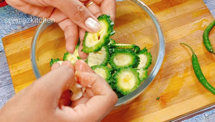 Wash and cut bitter gourd, removing hard seeds. Remove bitterness by salting and adding lemon juice for 5-10 minutes.
