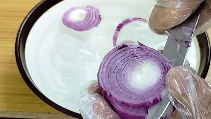 Peel and thinly slice the onions. Immediately place the slices in a bowl of ice water to prevent browning and keep them crisp.
