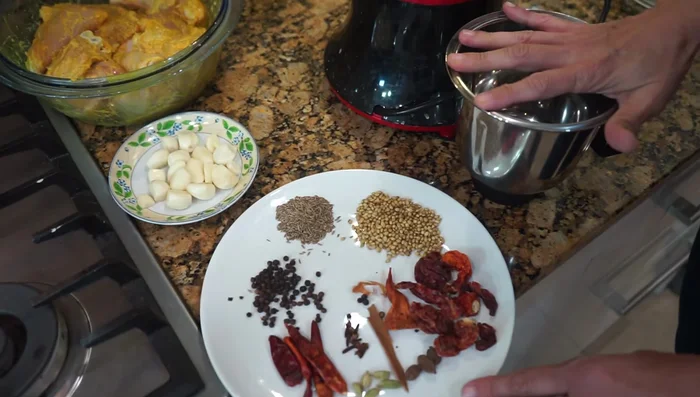 Grind the masala: In a mixie jar, coarsely grind the peppercorns, cumin, coriander seeds, mace, cloves, green cardamom, black cardamom, cinnamon sticks, and chilies.