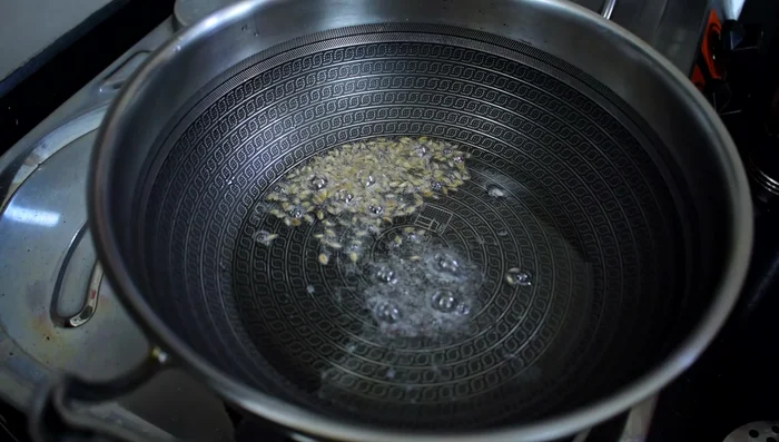 Add garlic, green chilies, and neem leaves (optional).