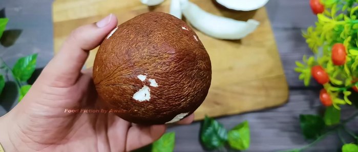 Obtain a whole coconut, ensuring the outer hard layers have been removed by the seller. Retain the coconut water.