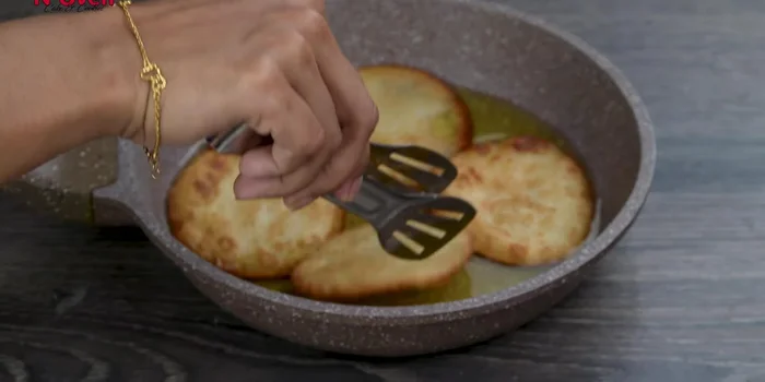 Remove each malpua and soak in warm sugar syrup for a few seconds.