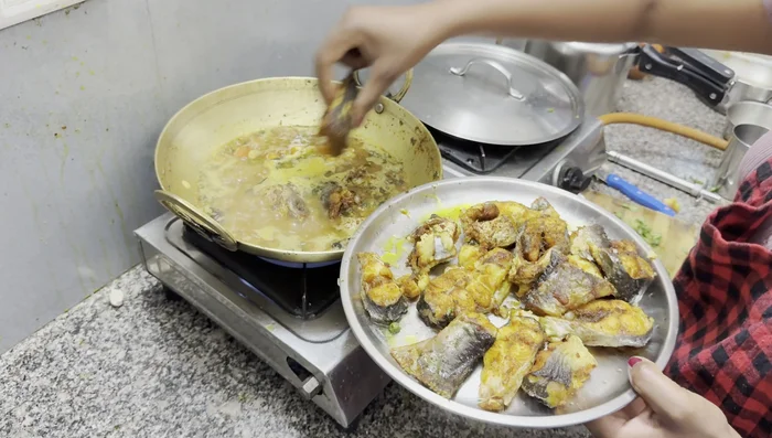 Add the fried fish pieces one by one to the boiling gravy.