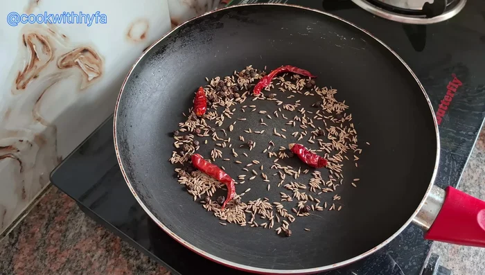 In the same pan, dry roast 1 teaspoon cumin seeds, 1 teaspoon black pepper seeds, 4 dried red chilies, 1 teaspoon poppy seeds, and 1 tablespoon coriander powder on low flame.