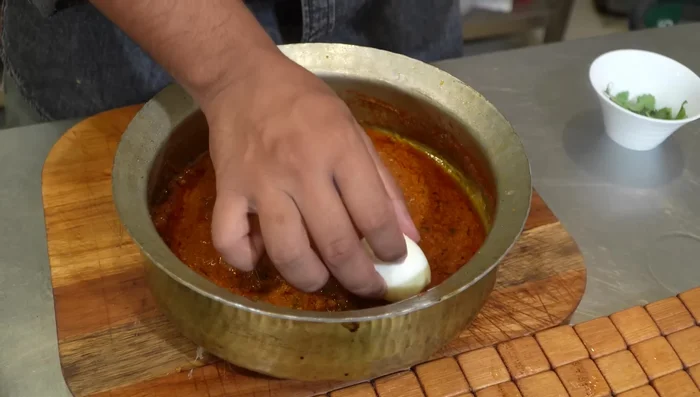 Layer the cooked biryani base with the hard-boiled eggs and the partially cooked rice.