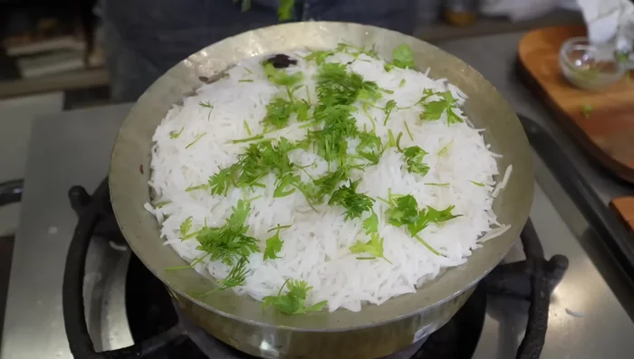 Add finely chopped coriander, mint leaves, rose water, kevda water, saffron threads, and fried onions. Cover and simmer for 10 minutes (5 minutes high heat, 5 minutes low heat).