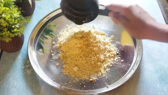 In a large plate, add gram flour. Break any lumps with your hands.