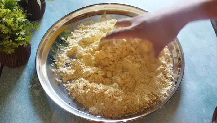 Gradually add the oil and water mixture to the gram flour, mixing thoroughly for at least 4-5 minutes until the dough is light and fluffy. Add a little water at a time to reach the desired consistency.