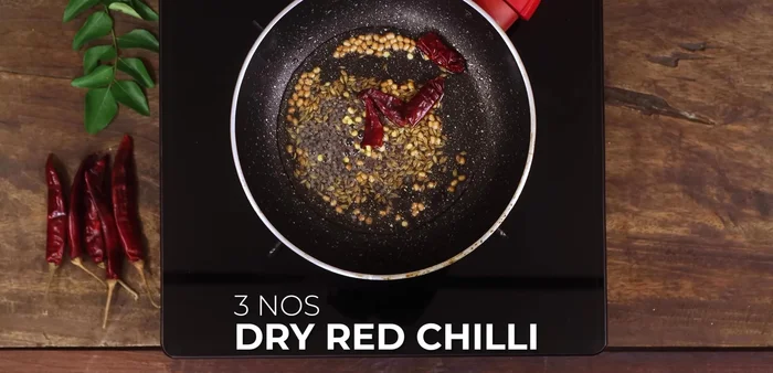 Add 3 chopped dried red chilies, 3 chopped green chilies, chopped ginger, and curry leaves.