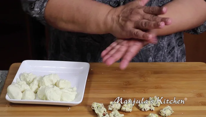 Roll each dough portion into a smooth ball, make a dent in the center, add filling, and seal it.