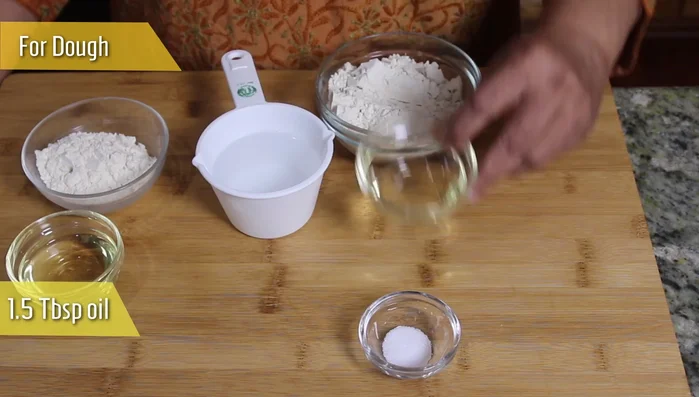 In a bowl, combine whole wheat flour, 1 tablespoon of oil, and 1/2 teaspoon of salt. Gradually add chilled water and mix to form a soft dough. Let it rest for at least 5 minutes.