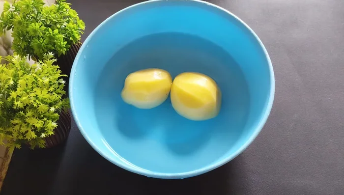 Peel and grate the raw potatoes. Immediately submerge them in water to prevent discoloration.
