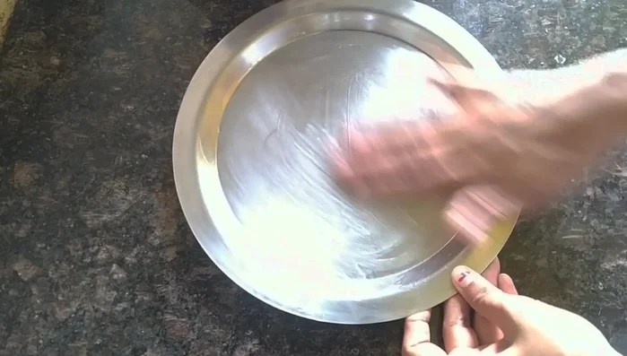 Lightly grease a plate with ghee (clarified butter). Pour the milk barfi mixture onto the plate and spread it evenly. Press gently with a spoon to flatten.