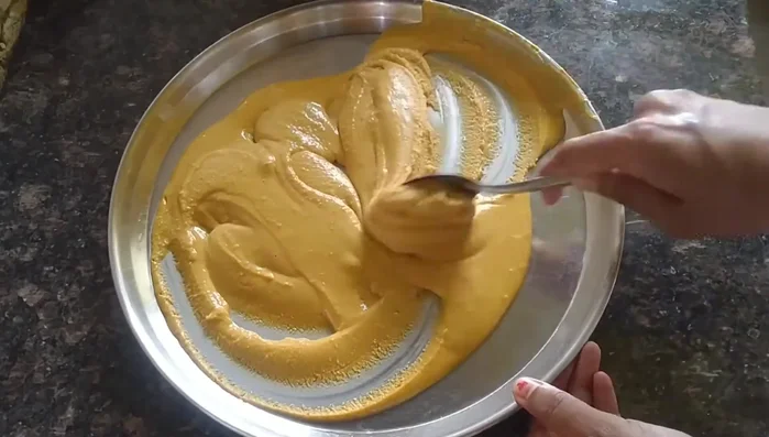 Stir the cooled gram flour with a spoon to distribute the heat and prevent burning.