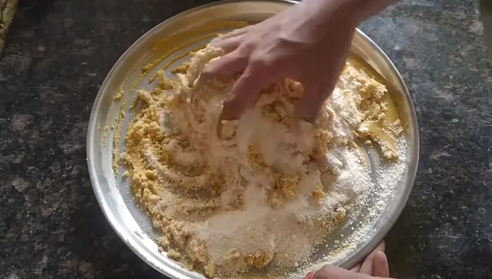 Mix the gram flour and tagar well with your hands, mashing to create a fluffy texture.