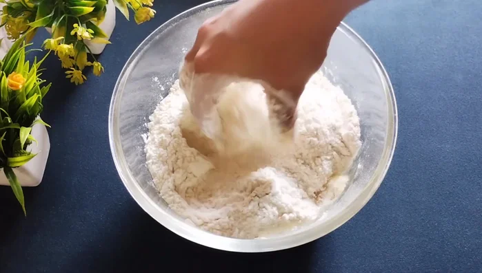 Add 1/4 cup of refined oil (or ghee) and rub it well into the flour until it resembles laddu crumbs.