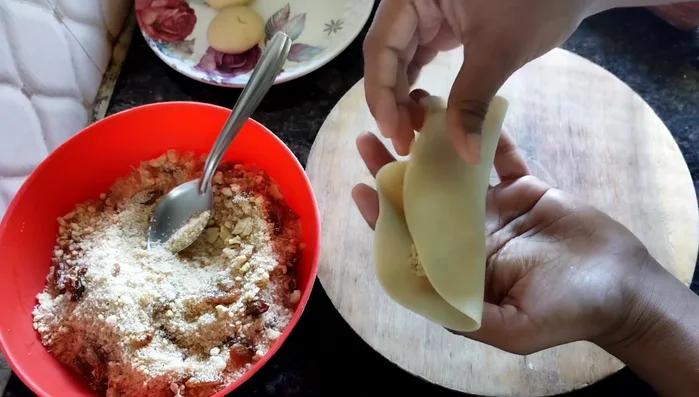 Moisten the edges with water, fold the dough over the stuffing, and crimp the edges to seal. Create a design on the top.