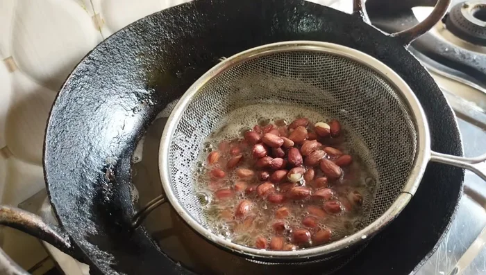 Fry the peanuts on low heat, stirring continuously, until they crackle and slightly change color.