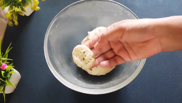 Using a slotted spoon, poke holes all over the mathri to prevent puffing during frying.