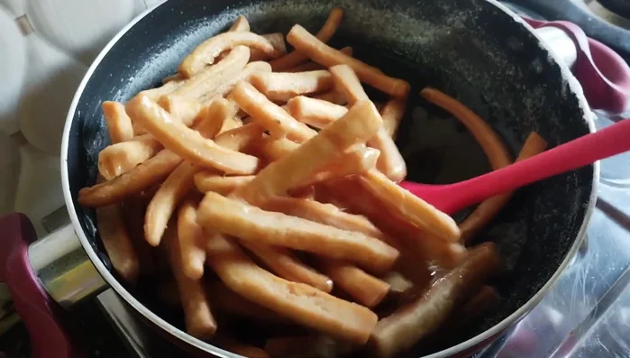 Add the fried and cooled Shakkar Para to the sugar syrup. Stir continuously to prevent sticking and coat the Shakkar Para evenly.