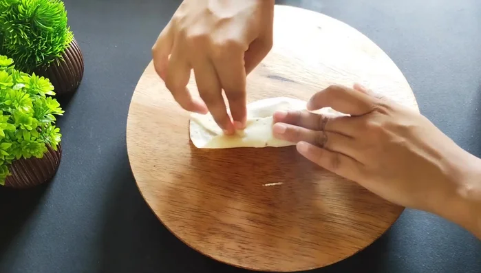 Fold the dough over the filling and seal the edges tightly, forming a half-moon shape.